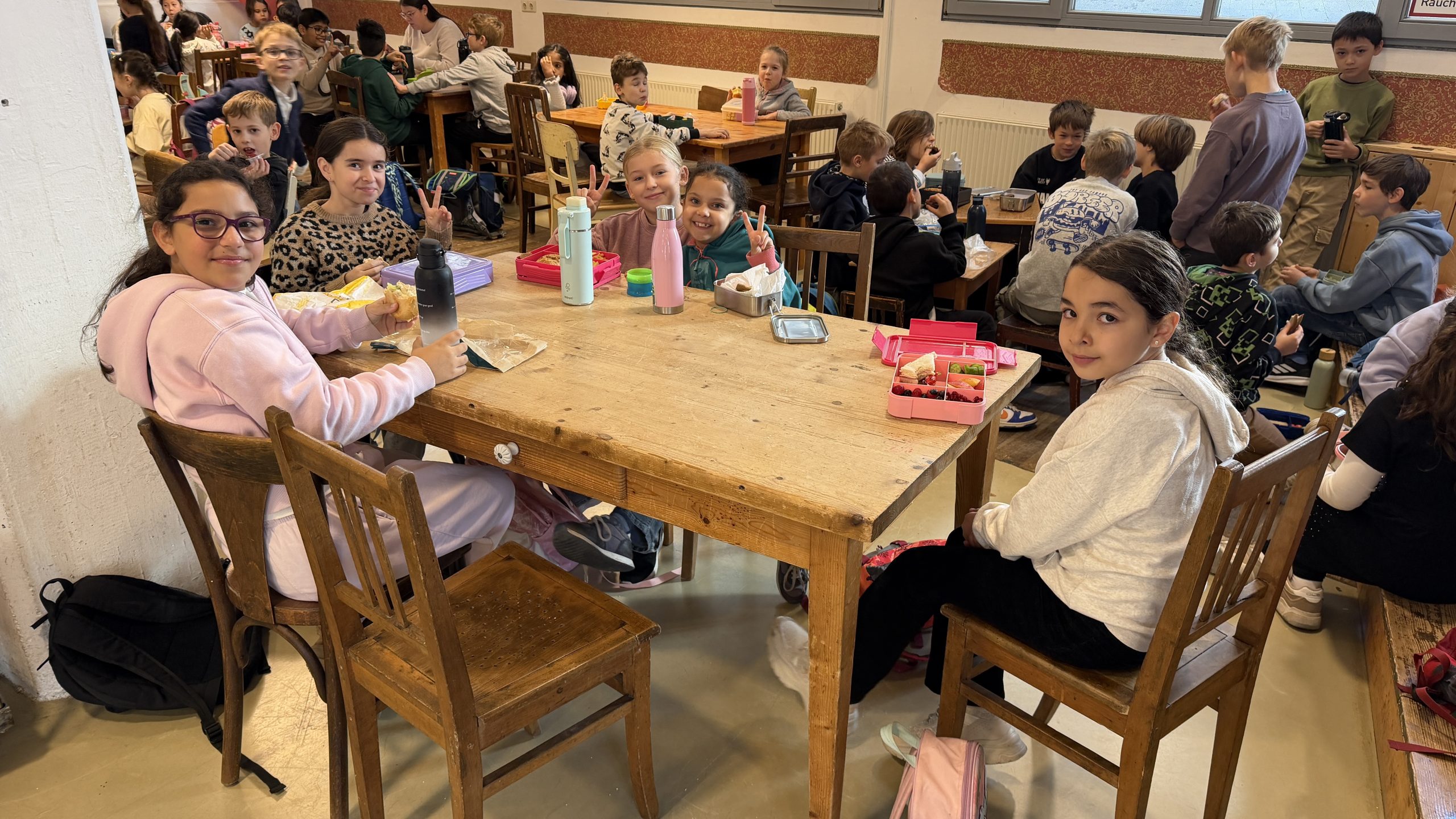 Kinder machen gemeinsam Brotzeit an einem Tisch im Theaterfoyer
